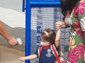 Toma de temperatura a una niña a la entrada de un colegio