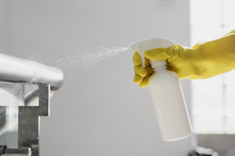 rubber-gloved-hand-holding-white-spray-bottle