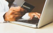 Persona comprando en línea en un ordenador con tarjeta de crédito