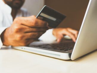 Persona comprando en línea en un ordenador con tarjeta de crédito